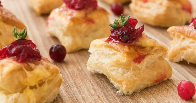 A close-up of a cranberry brie bites on a wooden plate.