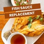 A small bowl of fish sauce sits on a wooden table next to a plate of fried fish.