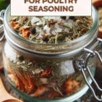 A glass jar filled with poultry seasoning on a wooden table.
