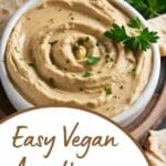 A bowl of hummus and pita bread on a wooden table.