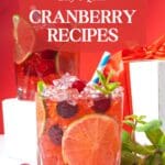 A close-up image of a cranberry mojito in a clear glass with crushed ice and mint.