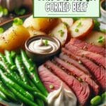 A plate of corned beef with green beans and potatoes on a table.