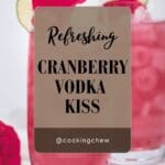 A refreshing cranberry vodka kiss cocktail with rose petals, garnished with a lime wedge.