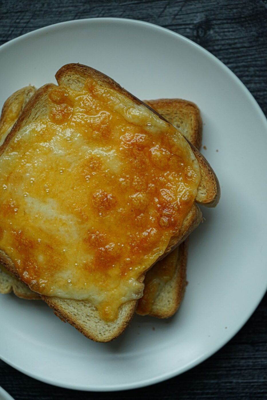 Golden brown, crispy cheese toast cooked in an air fryer, topped with melted cheese and herbs.