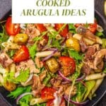 tuna salad with arugula, pasta and olives on a black plate.