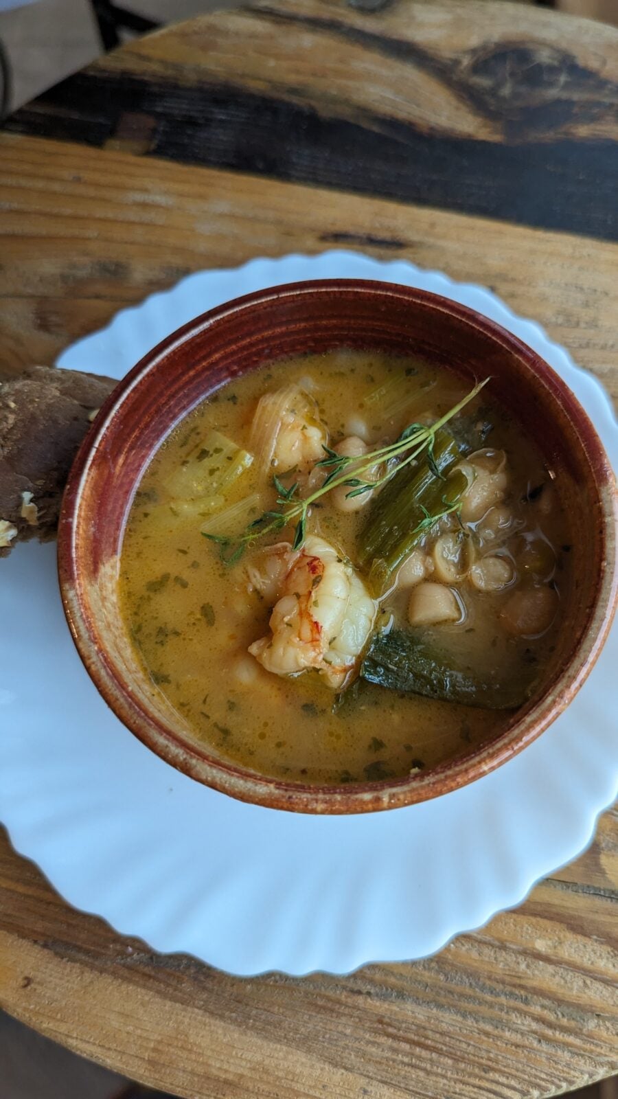 Lemony shrimp stew with white beans and leeks in a brown bowl on a white plate