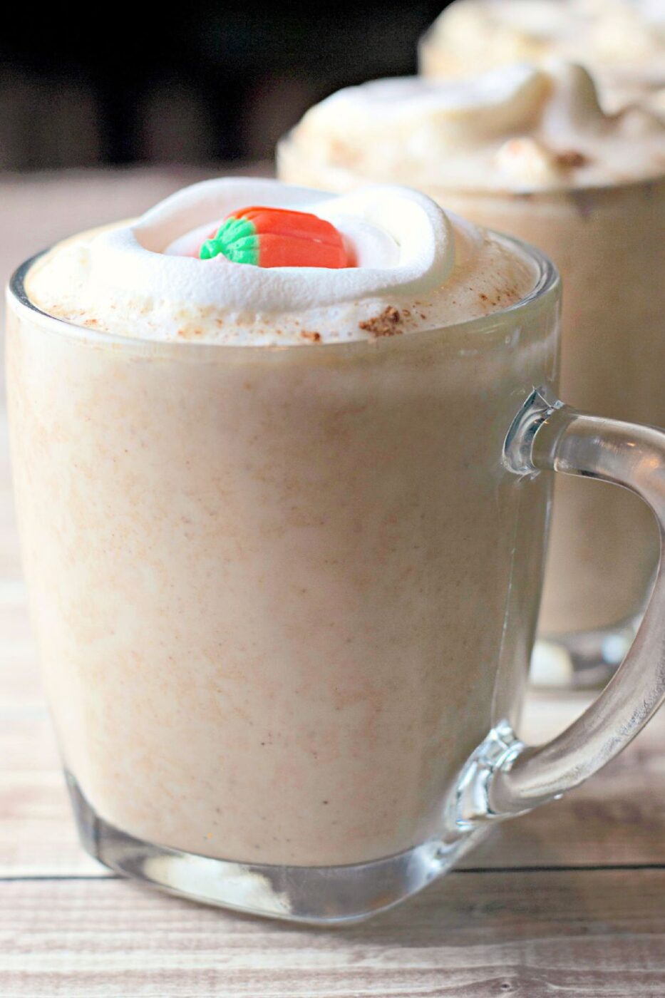 A mug of creamy pumpkin white hot chocolate topped with whipped cream and a cinnamon stick.