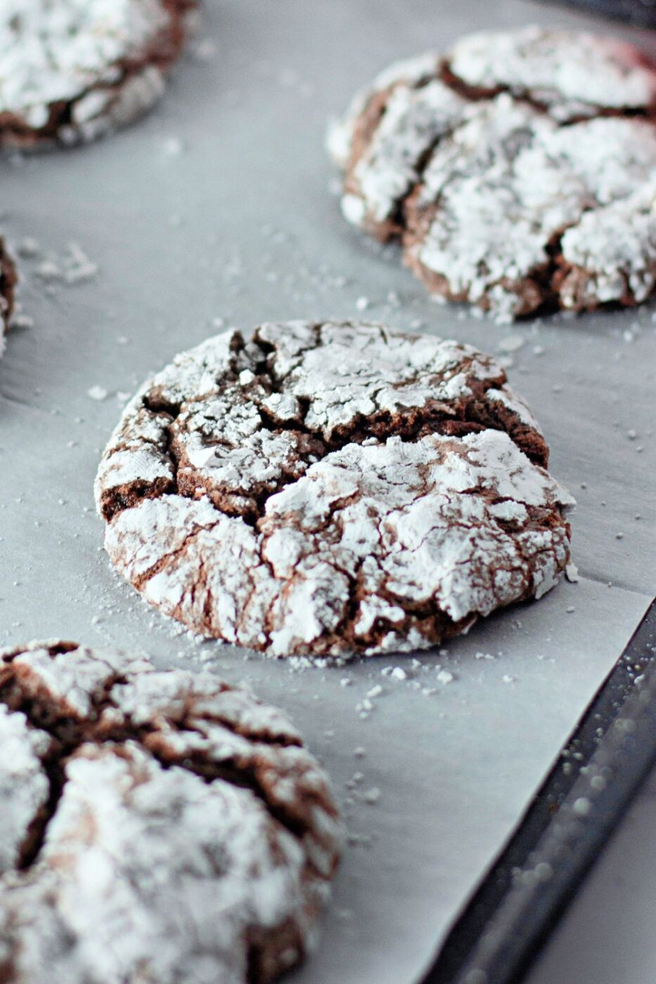A plate of dark chocolate crinkle cookies dusted with powdered sugar.
