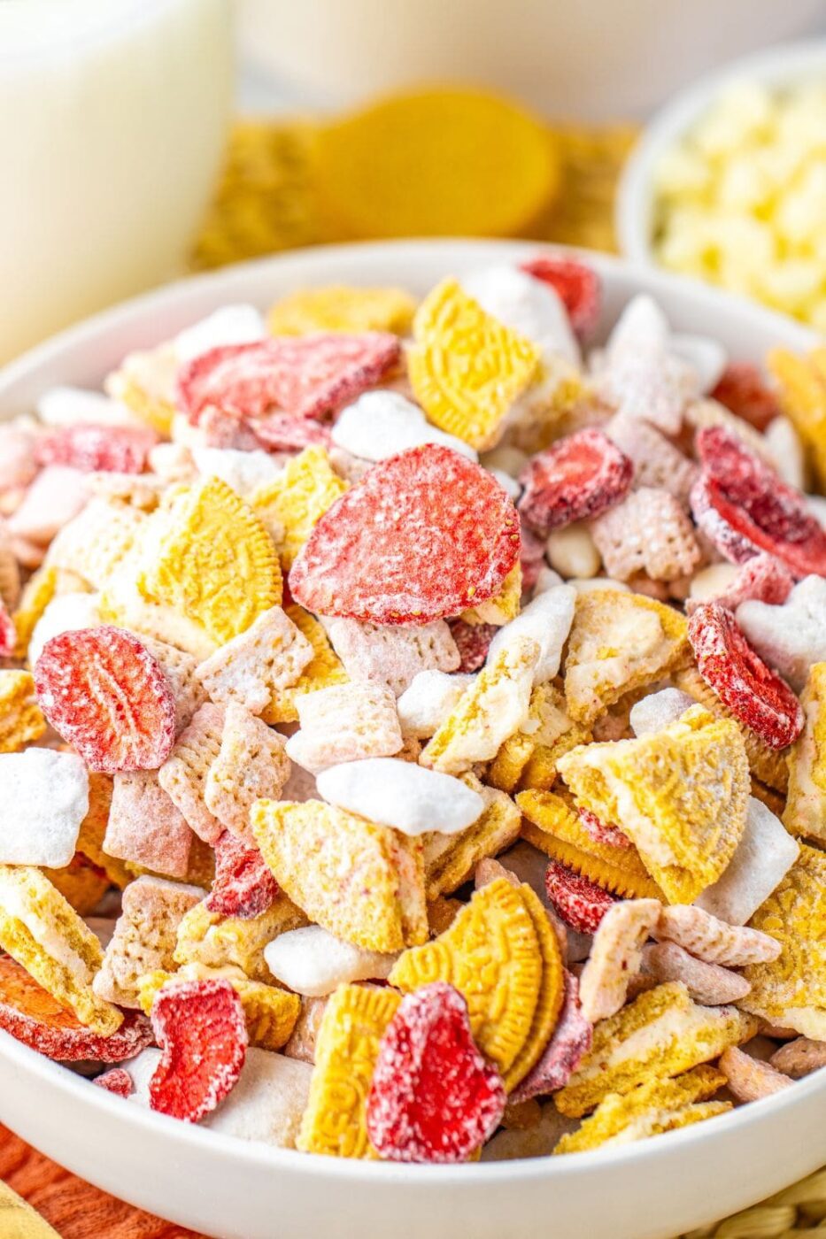 A bowl of pink strawberry shortcake puppy chow with white coating and sprinkles.