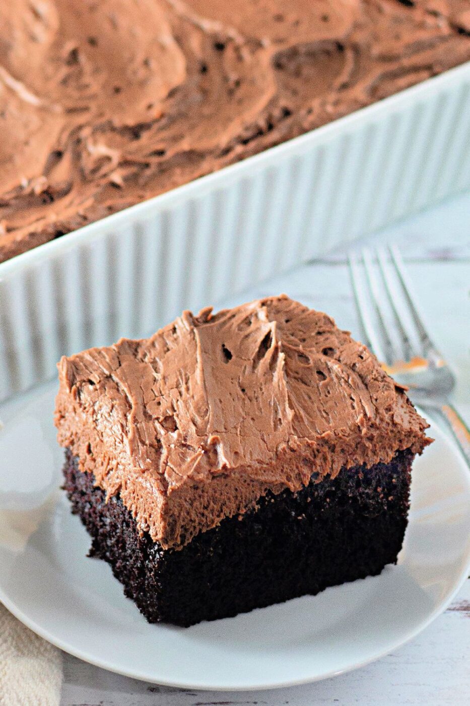 A slice of rich chocolate cake topped with swirls of chocolate buttercream.
