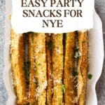 A plate of golden-brown fried zucchini sticks dusted with Parmesan cheese.