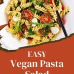 A close-up photo of a colorful pasta salad with a variety of vegetables and a light vinaigrette dressing.