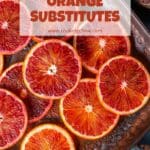 A photo of a bowl of blood oranges sliced in half on a patterned tabletop.