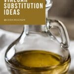 A glass pitcher filled with white balsamic vinegar sits on a wooden table.