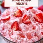 A bowl of strawberry pink fluff with whole strawberries on top.