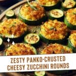A close-up photo of a wooden cutting board filled with baked cheesy zucchini rounds with panko crust.