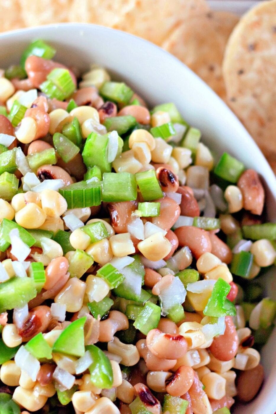 A colorful bowl of cowboy caviar, a corn and black bean salsa, with tortilla chips.
