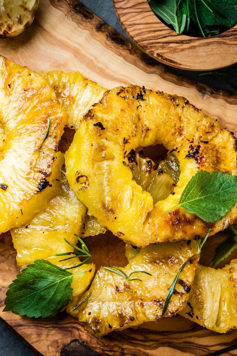 Golden grilled pineapple rings with visible char marks on a platter.