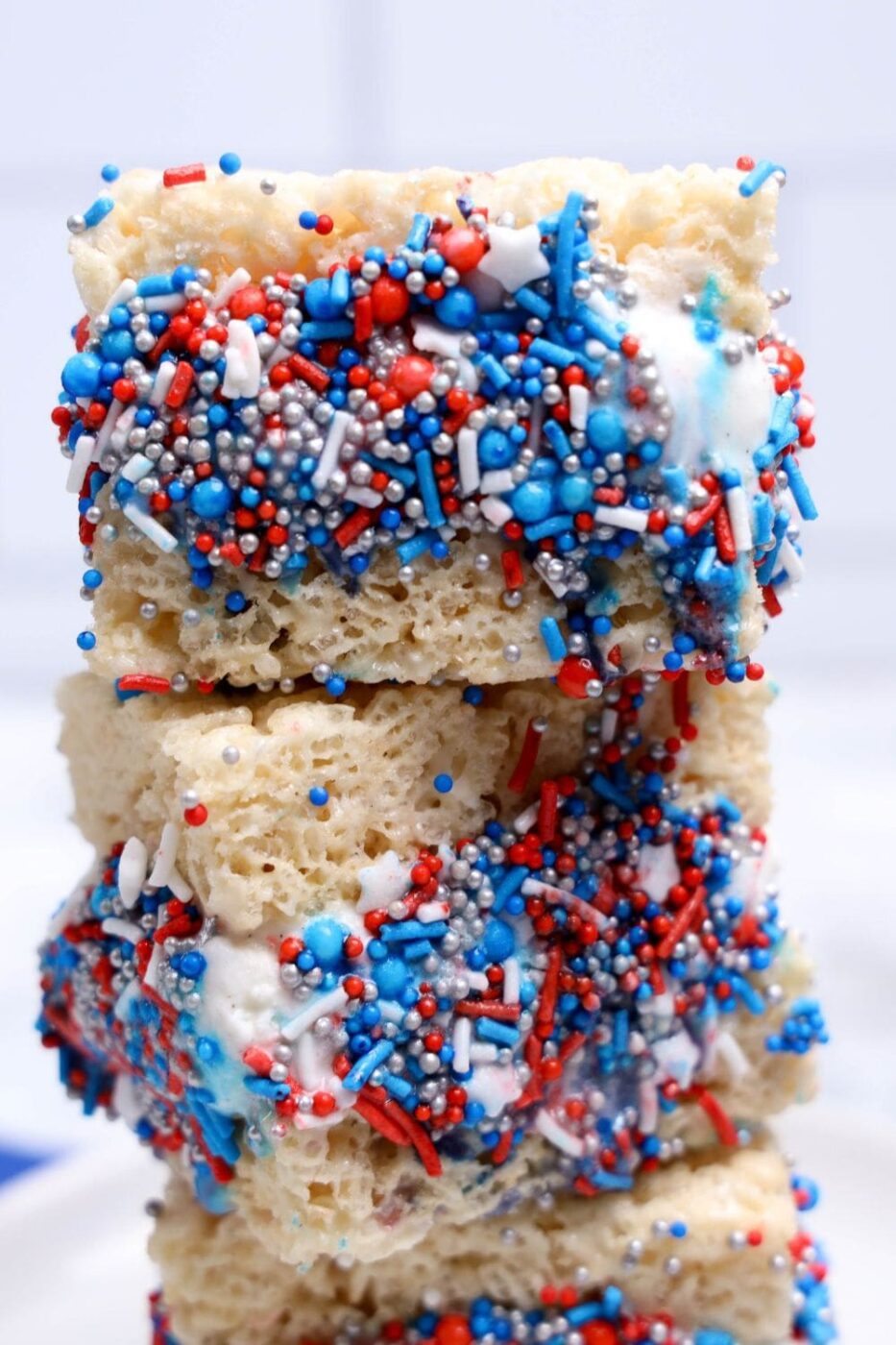 Red, white, and blue Rice Krispies ice cream sandwiches stacked on a plate.