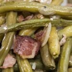 A serving of green beans cooked in the style of Texas Roadhouse, with visible seasoning and broth.