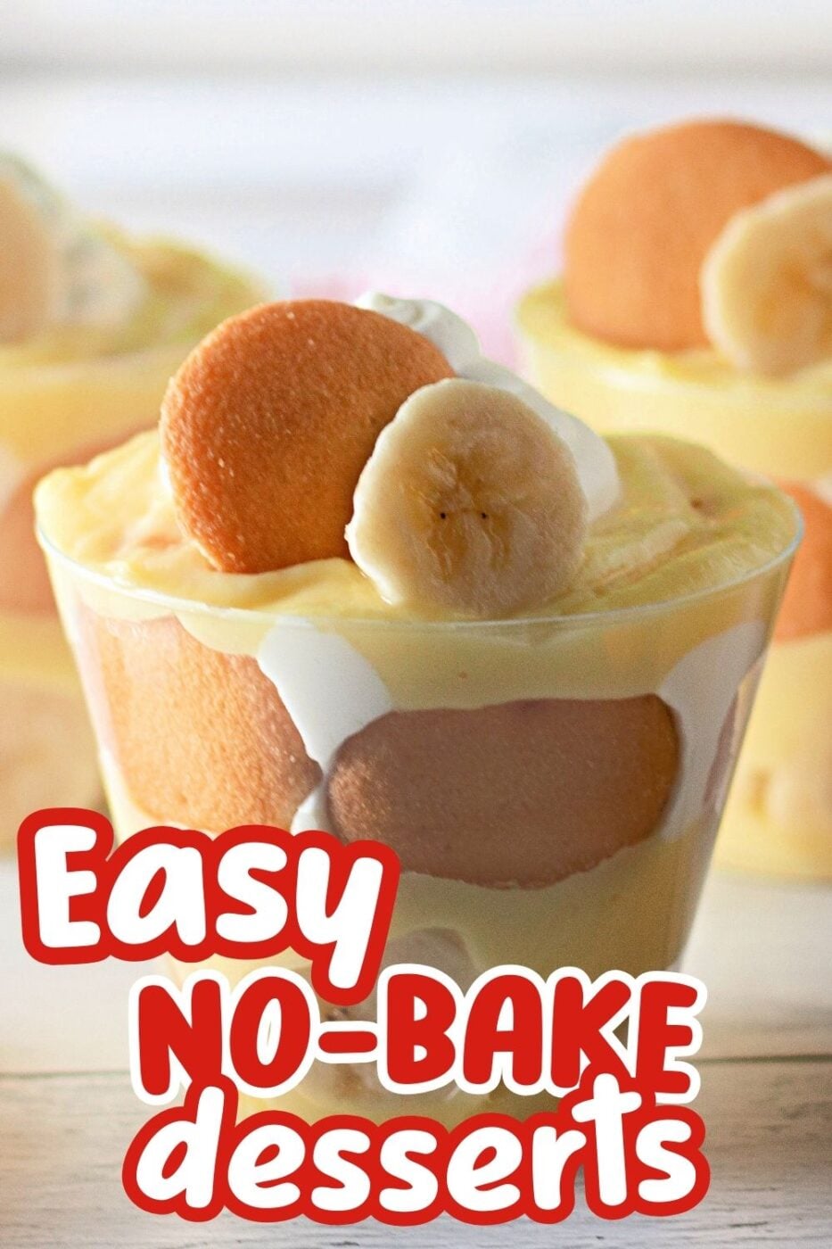 Closeup of a clear cup of layered banana pudding,topped with a vanilla wafer and a sliced banana