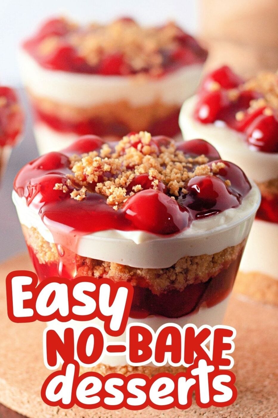 A clear cup overflowing with layers of no bake cherry cheesecake, made with cherry pie filling, graham cracker crumbs and creamy filling 
