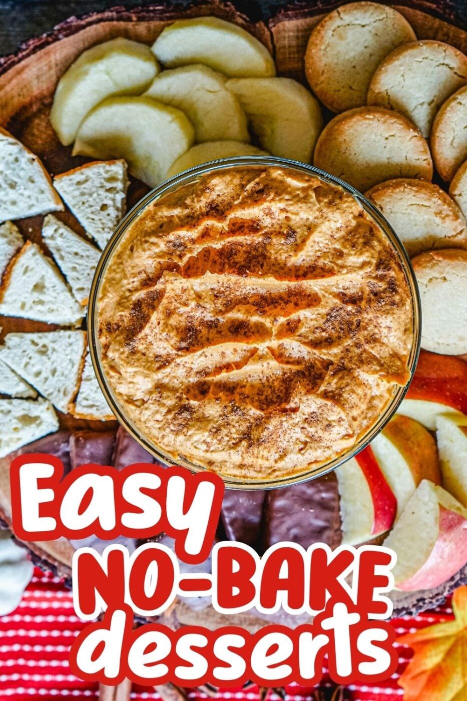 Top down view of a bowl with pumpkin fluff dip, surrounded by shortbread cookies, sliced apples, fudge cookies and sourdough pieces for dipping