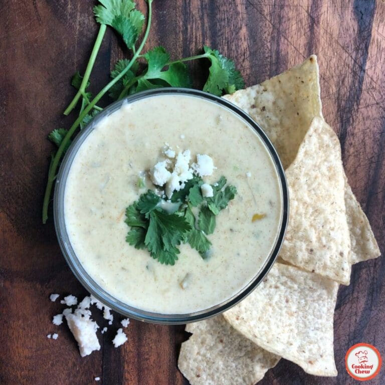 A festive bowl of queso dip with jalapeño slices and colorful chips.