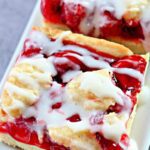 A pan of cherry pie bars with a beautiful vanilla glaze.