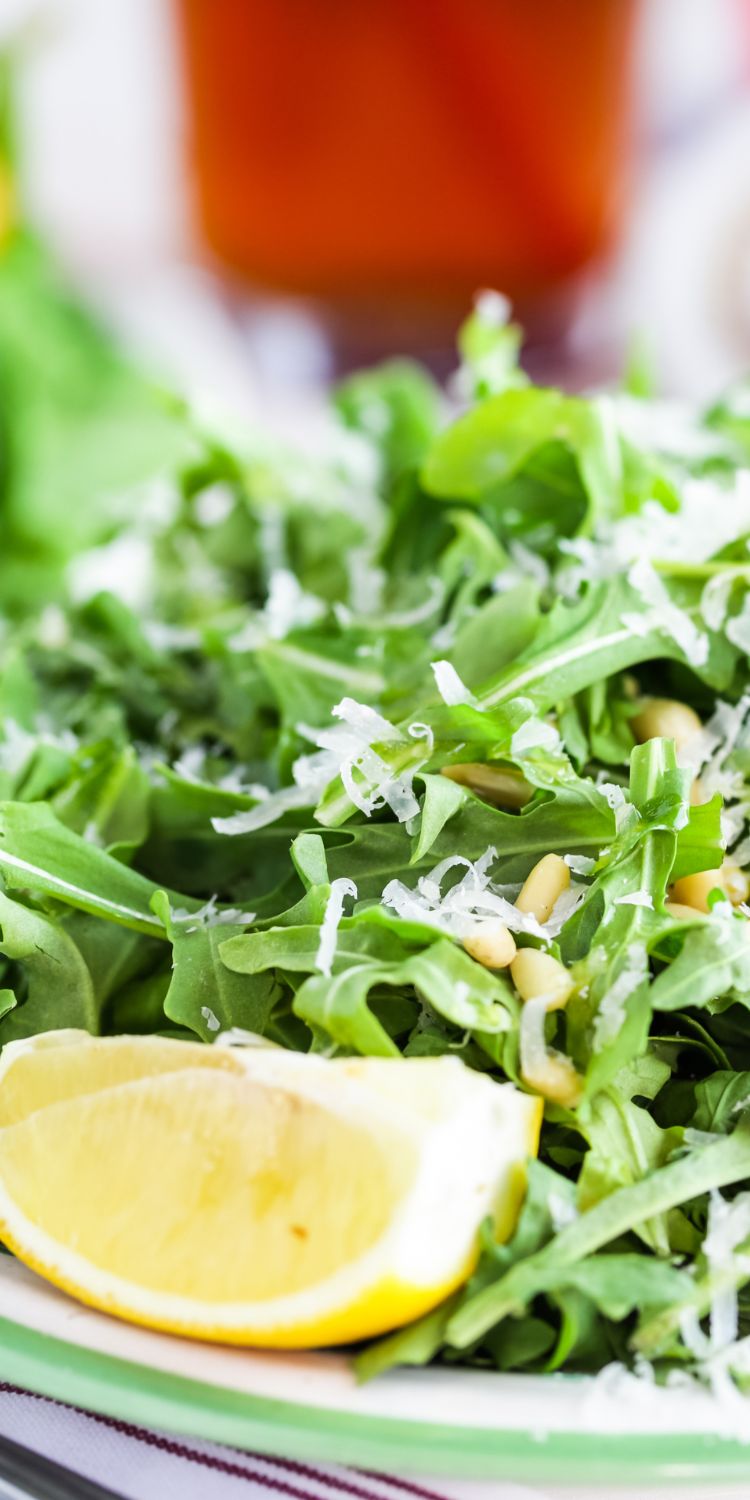 Arugula salad with shaved parmesan, pine nuts and a lemon wedge.