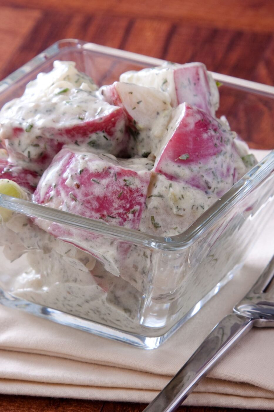 A bowl of creamy red potato salad with fresh herbs, ready to serve.
