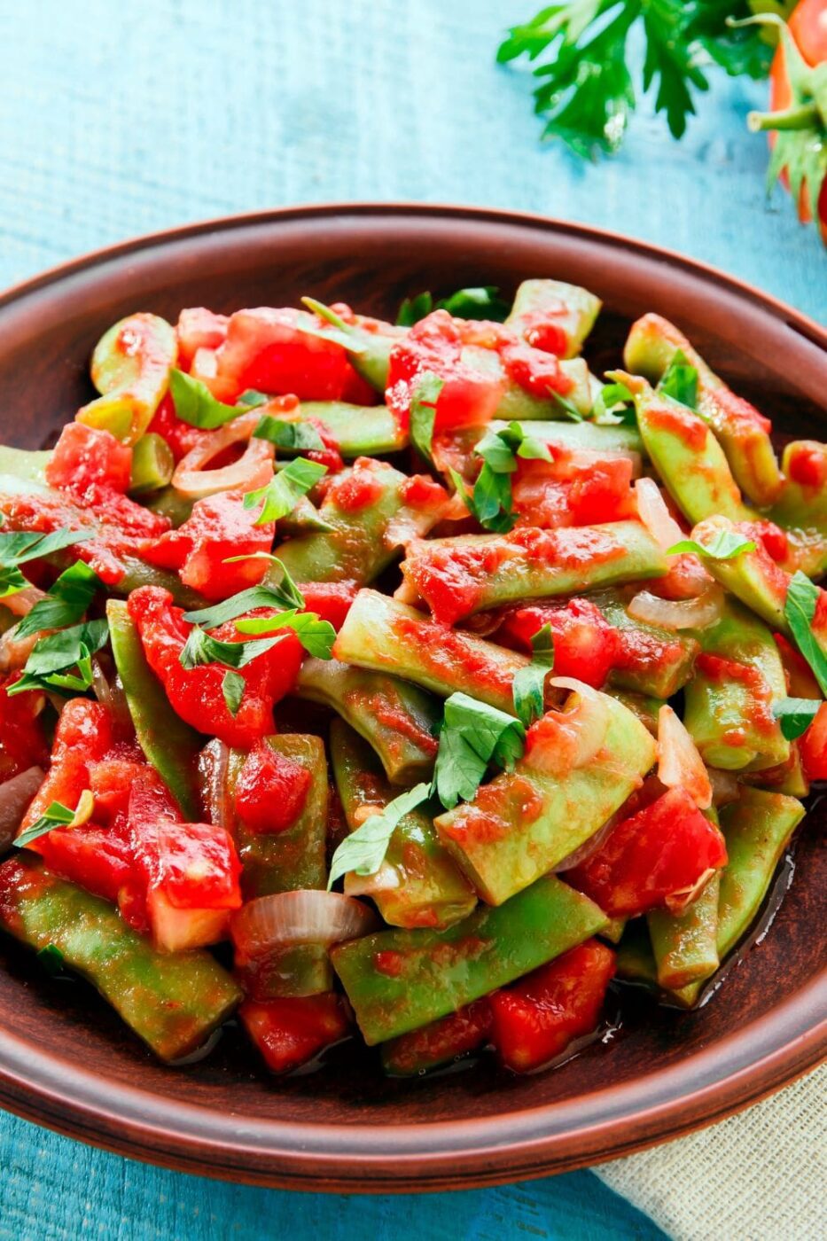 A vibrant bowl of green beans mixed with cooked tomatoes.