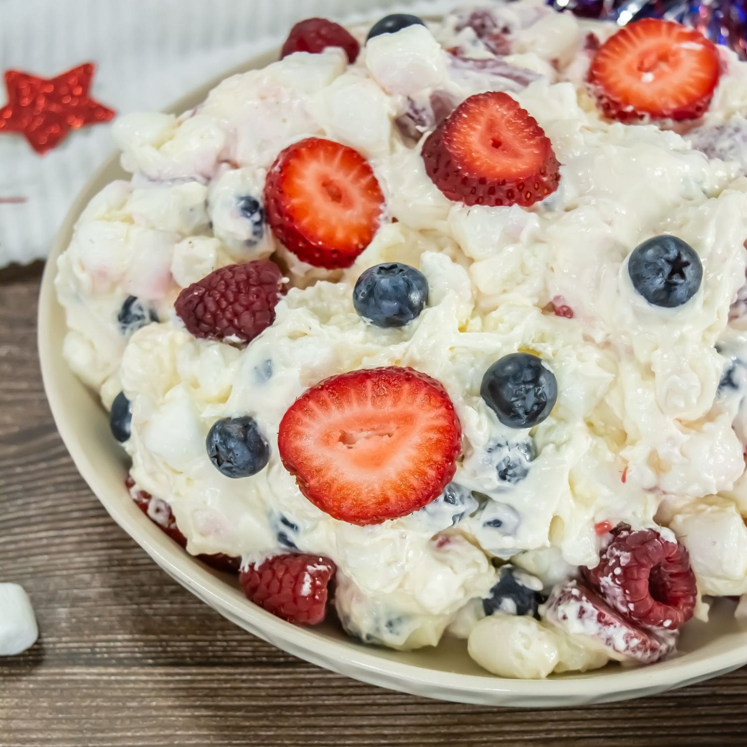 A large, inviting photo of the Red, White & Blue Cheesecake Salad in a clear serving bowl.