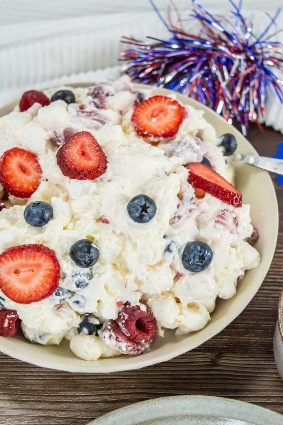 A vibrant bowl of red, white, and blue cheesecake salad with fresh berries.