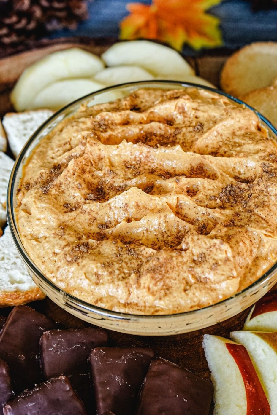 A bowl of fluffy pumpkin dip surrounded by cookies and pretzels.