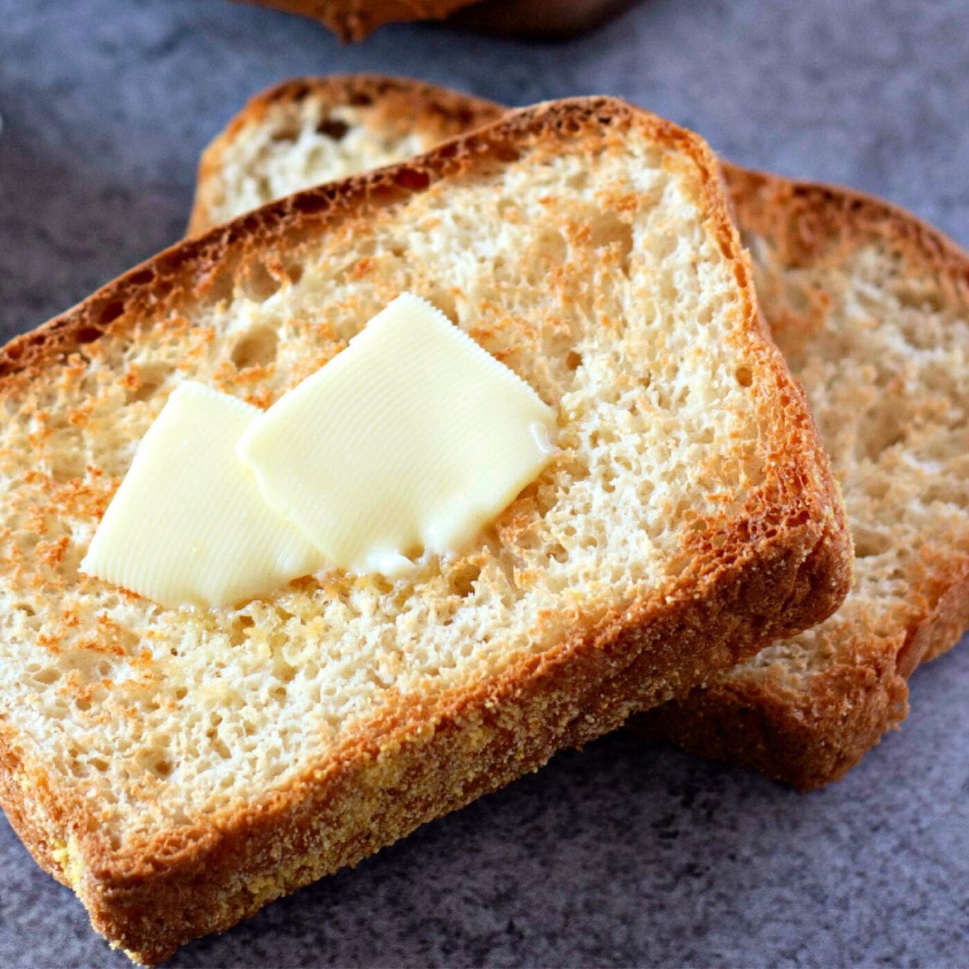 A wide, inviting shot of a sliced loaf of English muffin bread with butter.