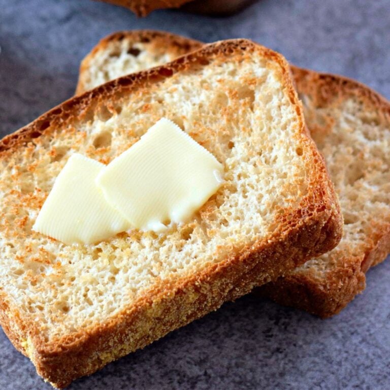 A wide, inviting shot of a sliced loaf of English muffin bread with butter.