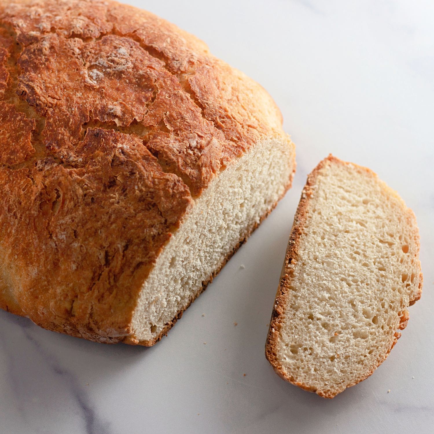 A wide, inviting shot of a freshly baked no-knead Dutch oven bread loaf on a cutting board.