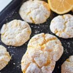 Lemon cookies dusted with powdered sugar on a summer-themed plate.