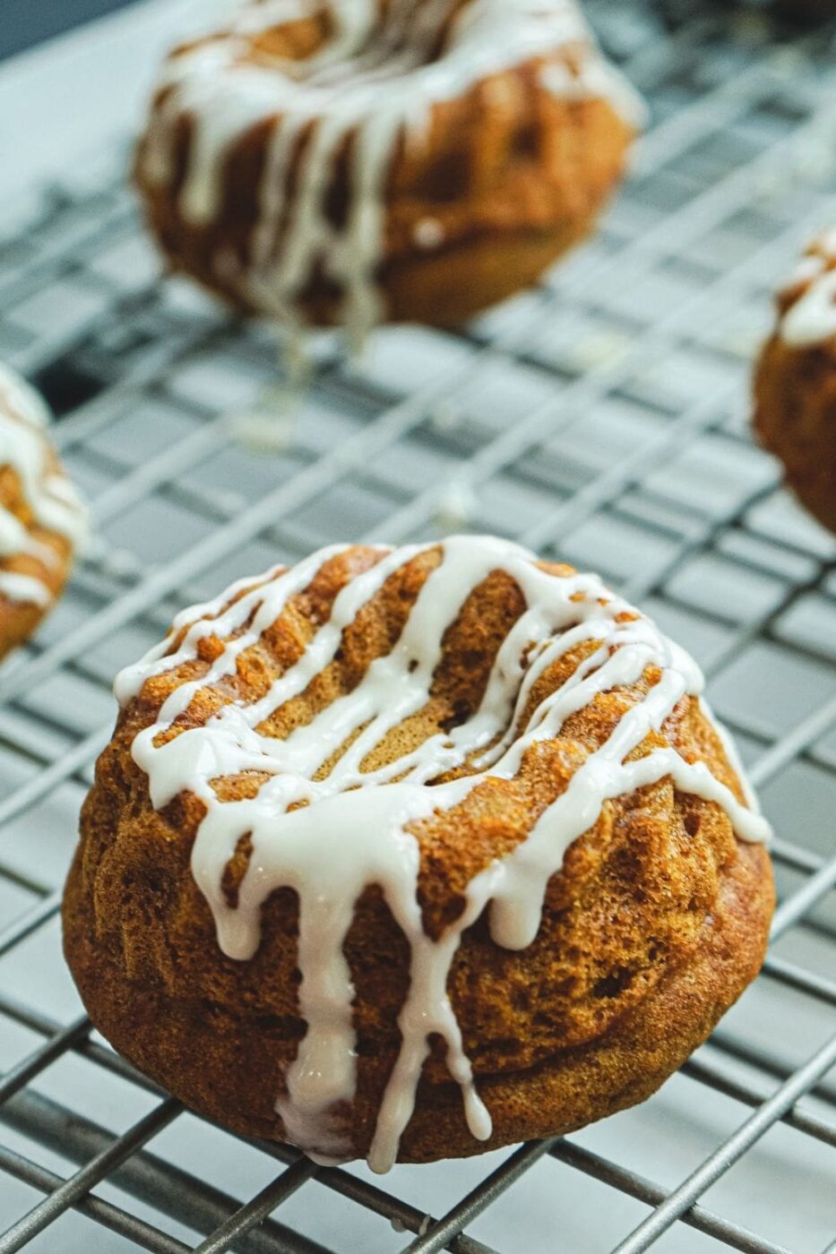 Individual mini pumpkin bundt cakes topped with icing on a tray.