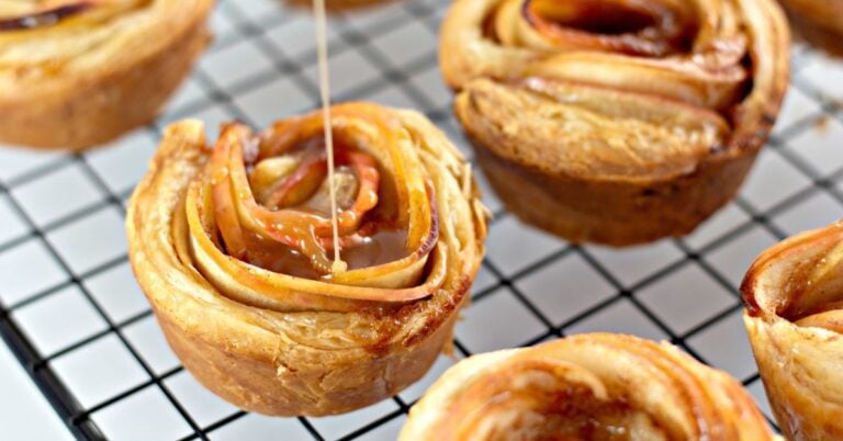 A whole apple rose tart, freshly baked and dusted with powdered sugar.