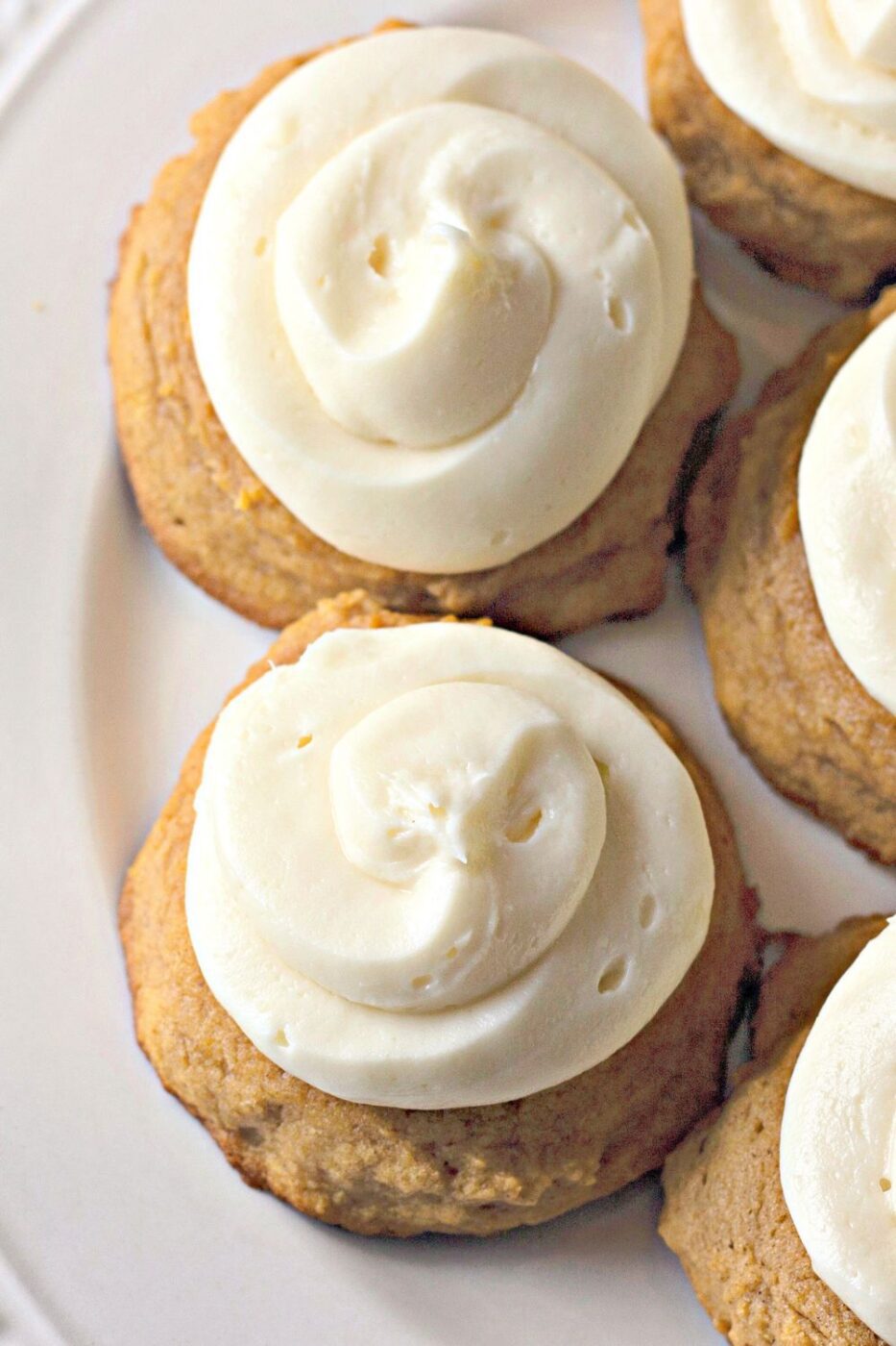 From-scratch pumpkin cookies topped with cream cheese frosting on a baking tray.