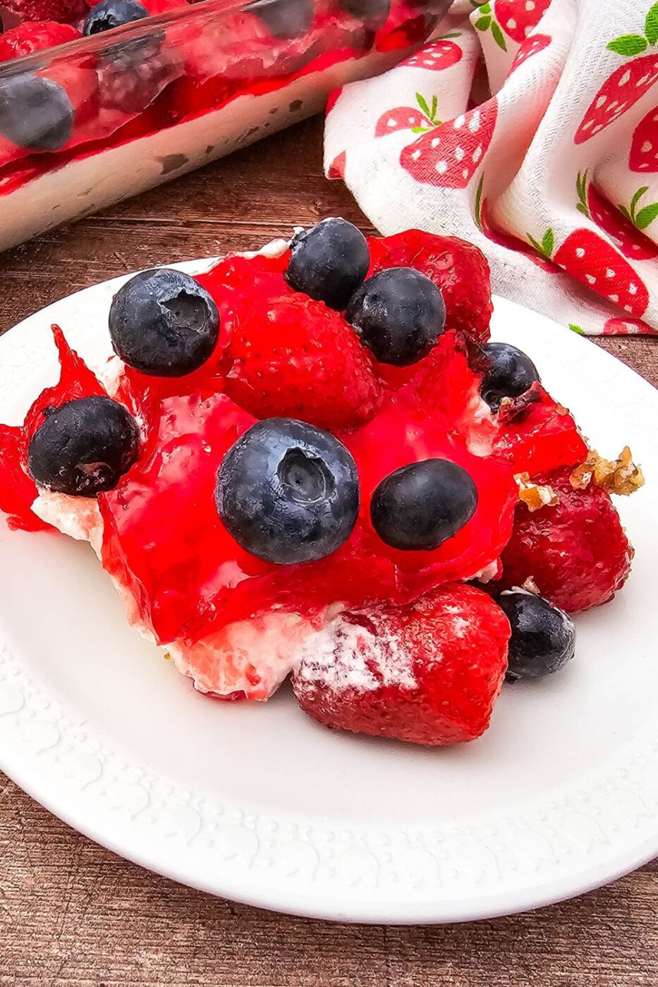 A slice of berry pretzel pie topped with strawberries and blueberries.