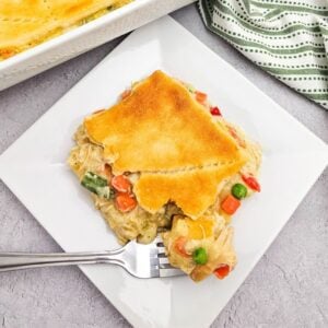 Chicken pot pie with crescent rolls served in a casserole dish and plated.
