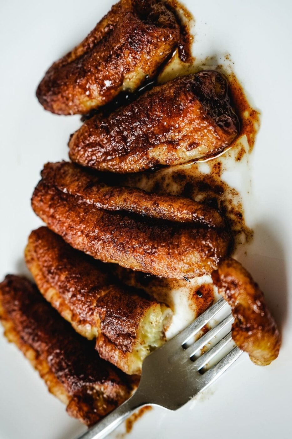 Air-fried banana slices on a plate sprinkled with cinnamon sugar.
