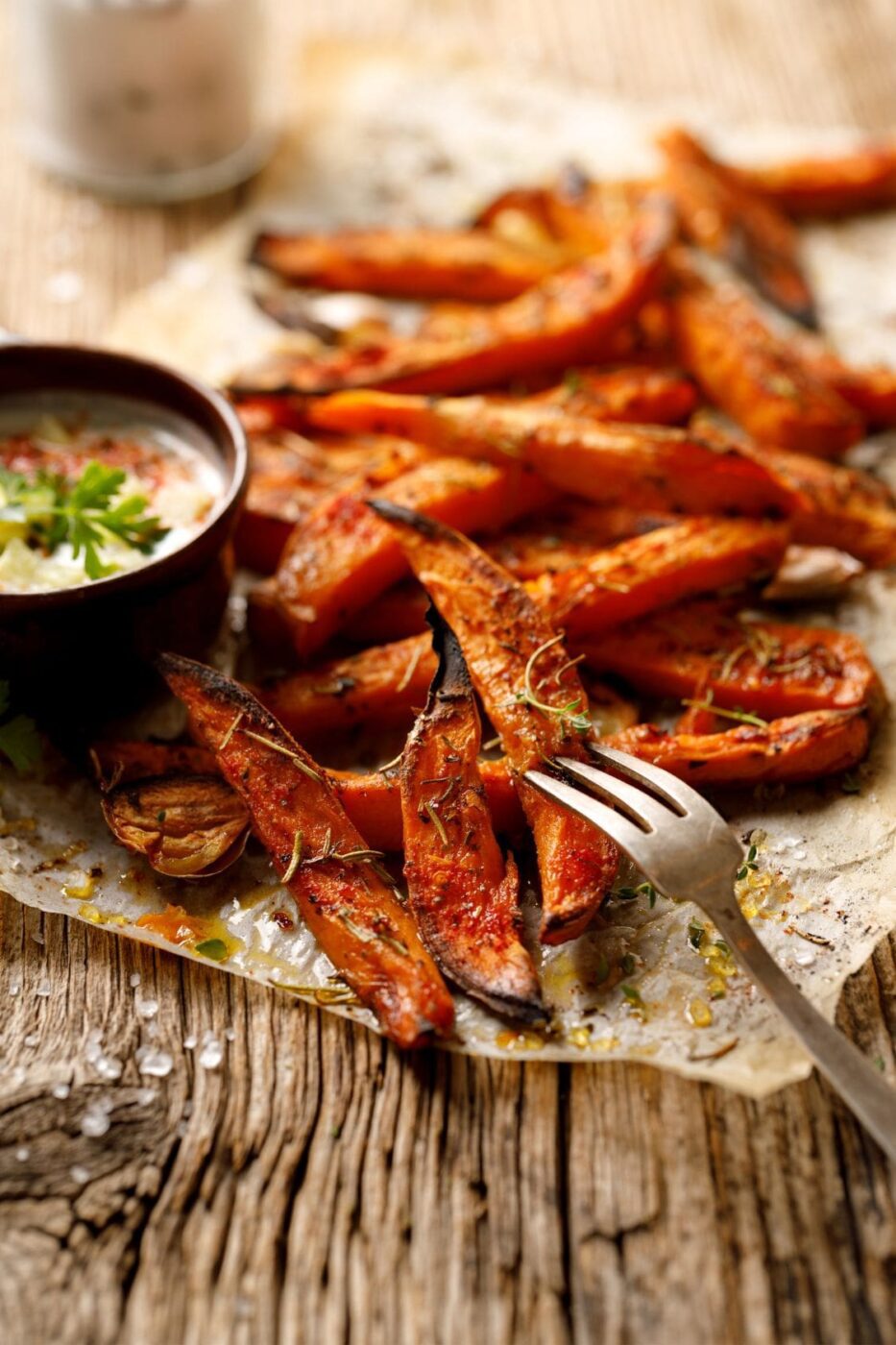 A basket of golden air-fried sweet potato fries with dipping sauce.