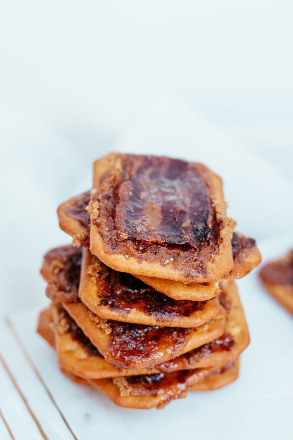 Baked bacon-wrapped crackers on a parchment-lined tray.