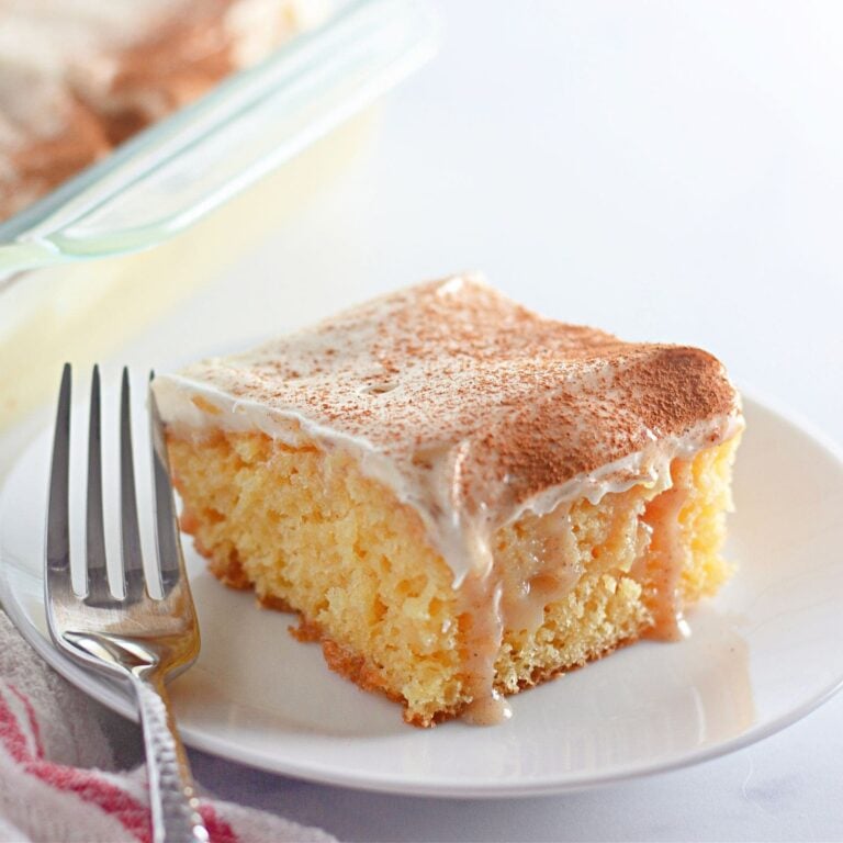 Hero shot of cinnamon roll poke cake slice with frosting and cinnamon sugar topping.