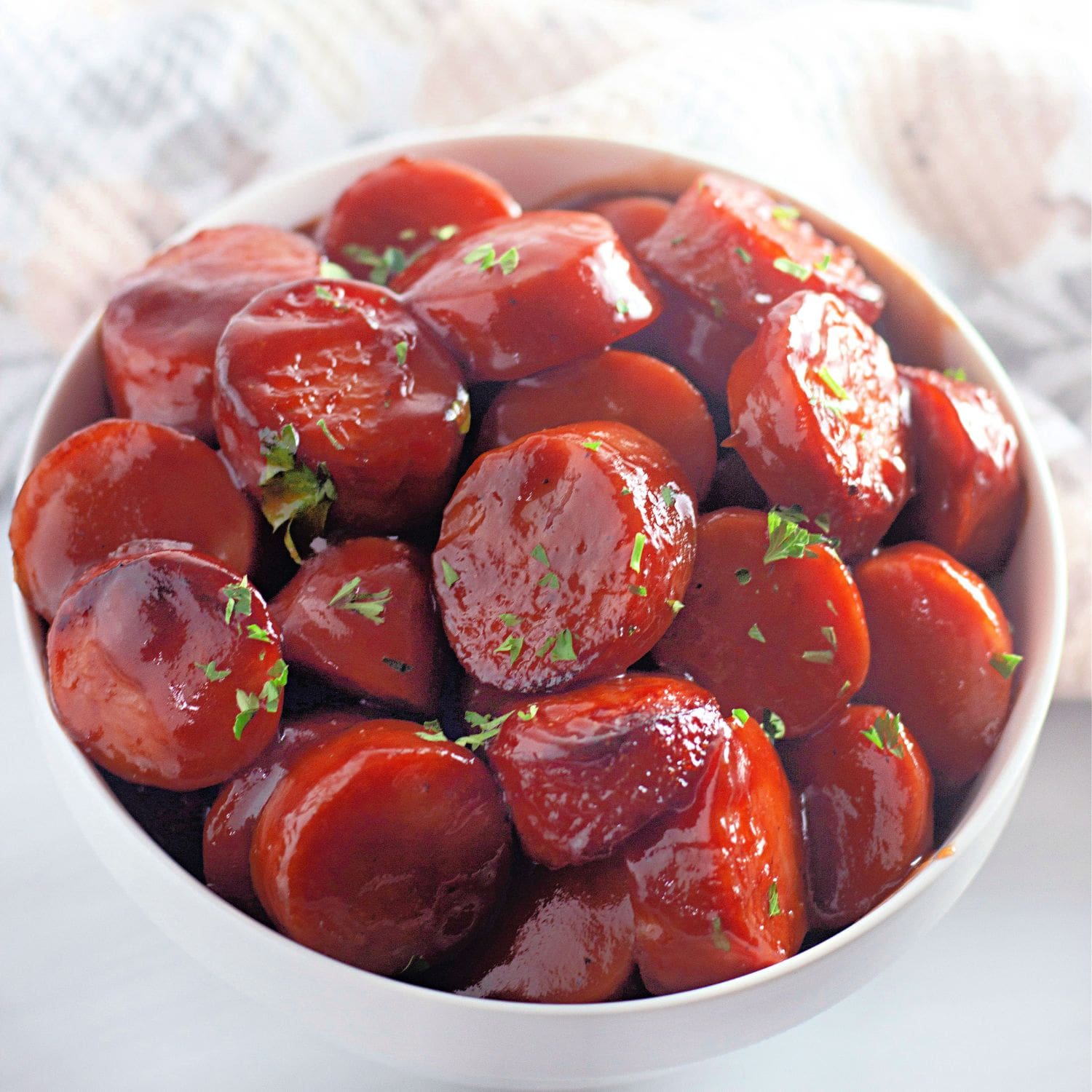 Glazed BBQ kielbasa in a bowl with parsley.