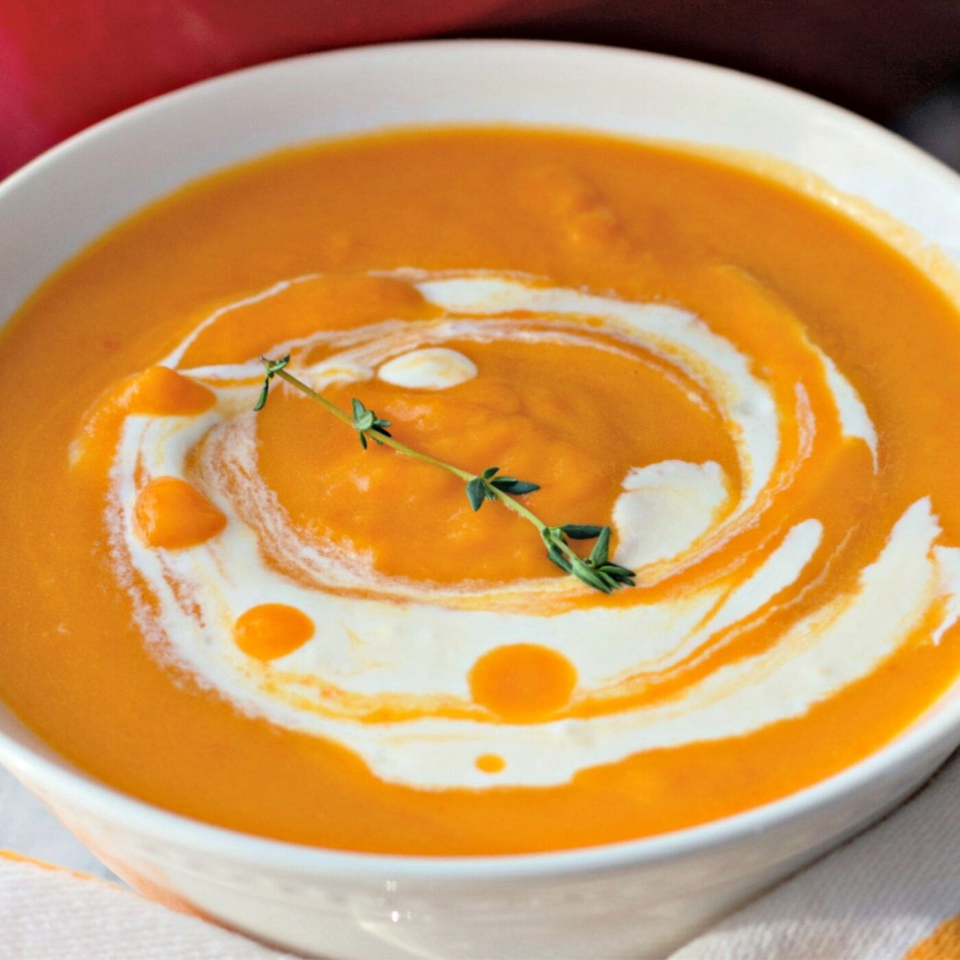 Close-up of creamy butternut squash soup with swirl and thyme.